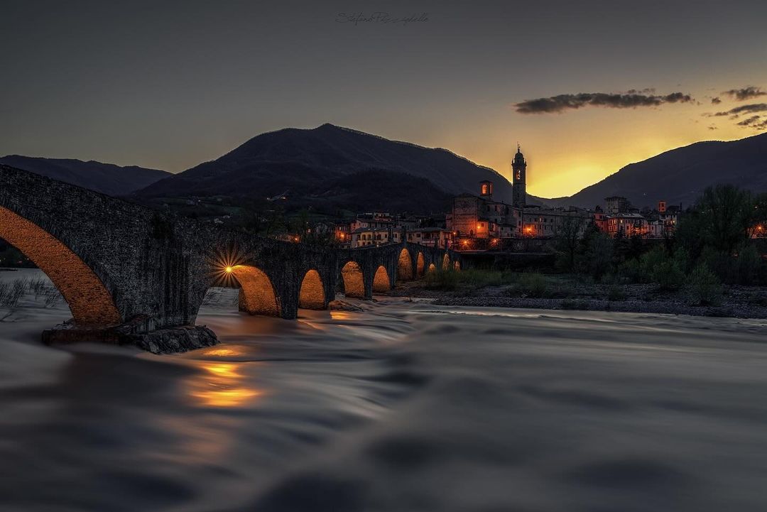 The warm lights of #Bobbio in the evening, emotion on the Trebbia 🌄 Ph. _piesse_82 | #inEmiliaRomagna