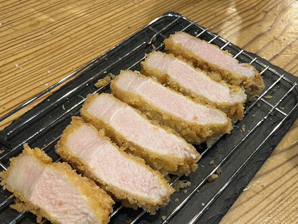 sekime_wacca's tweet photo. 【豚肉の加熱について】

結構、これ書くの悩んだんですよね。下手すると物議を醸しそうで…

カツカレーやるにあたって結構いろいろと実験したんですよ。

まず豚肉の火入れの前提として食品衛生法の加熱殺菌基準では63度30分相当の加熱が必要とされているんです。

63度30分相当ですので75度だと1分、70度だと4分、90度だと1秒となります。低温調理の場合、主要食中毒菌の生育限界の55度でなら5時間必要となります。

さて、なぜ豚肉が牛肉や鶏肉と違って加熱条件が違うのか？それは豚って生育過程で高確率でE型肝炎ウ イルスに感染し、それは肉の内部汚染であって残存もしている可能性があるからとのことです。SPFも肝炎は対象外ですしね。

E型肝炎ウ イルスを不活性にする安全基準として63度30分相当が設定されています。（一応、厚生労働省の実験データとしては68度5分でも検出されなくなったそうです。）

さて、話を戻します。

昨今のロゼに火入れしたとんかつやミシュランとか立派なレストランで出てくる豚肉のソテー。

63度30分相当の基準を満たしてると思いますか？

私見ですが、限りなくアウトに近いと思う所も少なくありません。

下の写真はうちのとんかつです。
左は肩ロース、右はロース。

ロースって火を入れるとすぐ白くな���ます。一方、肩ロースは白くなりにくく赤さを保ちやすいです。

ちなみにリブロースだと、脂側のかぶりの部分は肩ロースと同じ肉質なので赤いけど、下の部分のロース芯は白くなります。

さて、このポストで何が言いたいかというと、低温調理以外の加熱方法で63度30分相当基準で加熱した場合、ロースやヒレはほぼ確実に中心までしっかりと白くなるという事です。

一方、肩ロースは赤さを残す事がギリギリ可能です。いわゆるロゼですね。なので、同じ温度と時間でも部位の違う左と右の写真の赤さが違うのです。

ちなみに、低温でじっくり揚げる昨今流行りのとんかつ。

当店の実験では厚さ2mmのカツを120度で10分揚げると、揚げ上がりの芯温は47度。これでは話になりませんので15分間揚げます。すると揚げ上がりの芯温は62度。そしてピーク温度が3分50秒後で66度。そして10分後に65度と下がってきます。

その10分後の65度の段階でカットした断面が4つ目の写真。
見た感じは十分揚がっているように見えますね。でも、63度30分相当の基準は満たせていません。

厚生労働省データの安全を見ないでギリギリの68度5分相当だと、ギリギリ満たせているか満たせていないかの境界線です。

ちなみに、150度6分30秒だと、揚げ上がりが56度、4分15秒後の72度をピークに6分15秒で71度と下がってきます。これだと完璧に63度30分相当を満たします。でも、ロースの場合はうっすらピンクの部分すらほぼありません。

つまりですね…ロースやヒレで中心がピンクだと、おそらく食品衛生法の基準は満たせていない可能性が高いと思ってくださいという話です。あ、肩ロースはピンク残しは可能ですし、うちのとんかつはピンク残ししてます。

あと、火を入れない方が美味しいかどうかの話。

個人的には焼肉ではまあまあ焼きます。なぜかというと、焼いた方が芳香成分やアミノ酸などが複雑な化学反応を起こした結果、美味しく感じる香りや成分が増すからです。

つまり、レアよりは火を入れた方が美味しい条件が増えるんですよね。ただし、肉汁は失われますし食感は固くなっていきます。なので、表面こんがり、芯はしっとりが理想です。

とんかつの場合、せっかく生産者の方が心血注いで育てられている訳ですから、料理人としてはポテンシャルのMAXを引き出したいですよね。

柔らかく、ジューシーで、でもレアではない火入れ。そして食品衛生法の基準を満たす…これ、ほんとめちゃくちゃ難しいんですよね…