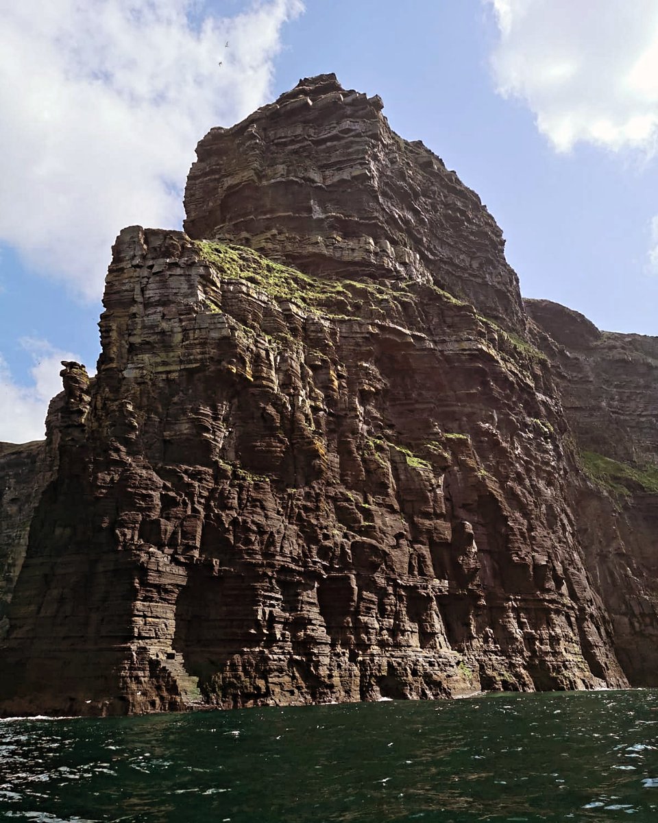 Looking up from beneath, the Cliffs of Moher form a formidable stone fortress. County Clare, Ireland.