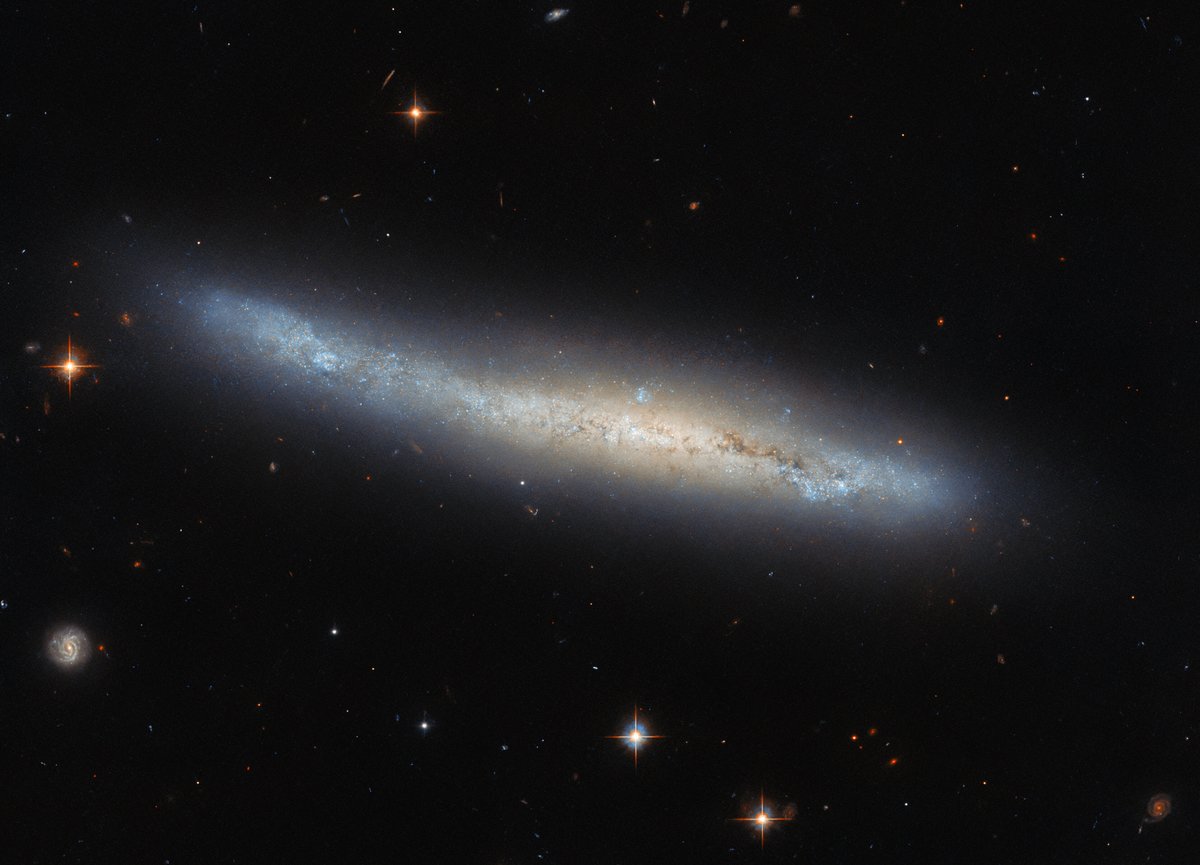 Galaxy NGC 4423 may look like an oddball with an elongated shape, but in fact it is a fairly typical spiral galaxy seen from the side. In a well-placed coincidence, a more distant face-on spiral can be seen to the lower left. Credit: NASA, ESA.