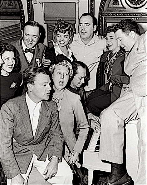 During a stop on the Hollywood Victory Caravan, Spring 1942. Top row from left: Cary Grant's nose, Fay McKenzie, Stan Laurel, Frances Langford, Pat O'Brien, Rise Stevens, Frank McHugh. Seated: James Cagney, Charlotte Greenwood, Groucho at piano. Don't know what song he's playing.