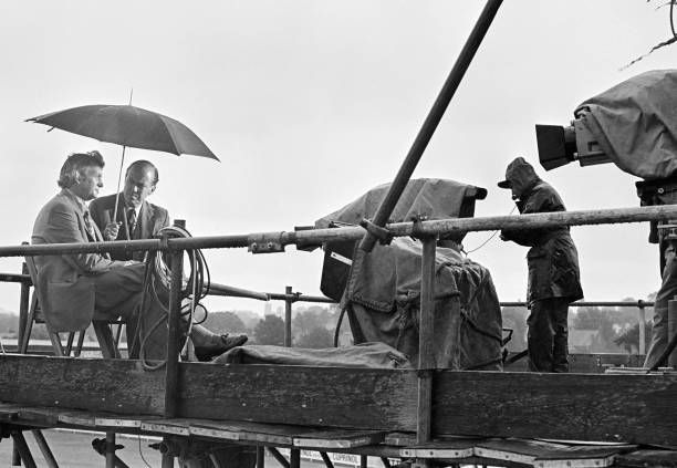 In the days of old the BBC used scaffolding to erect bases for their TV cameras and in intervals the presenters clambered up, often by ladder, to chat ... here Peter West and Richie Benaud ignore wind and rain at Edgbaston, 1st Ashes Test, July 10th 1975