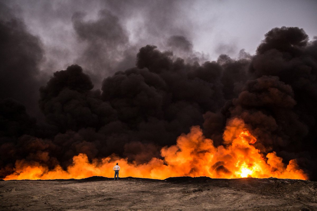 A man stands in front of an oil fire burning in the Qayyarah area during the operation to recapture the Iraq's second largest city of Mosul from ISIS, on October 19, 2016 🇮🇶 📷: Yasin Akgul | Getty Images