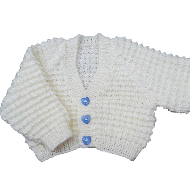 Looking for the perfect gift for a newborn or a reborn doll? Discover this cream, hand-knitted baby cardigan with adorable blue heart buttons. Only at #Knittingtopia on #Etsy #Handmade #KnittedBabyClothes etsy.me/48qx2B1 #uksmallbiz #handmade #MHHSBD #craftbizparty