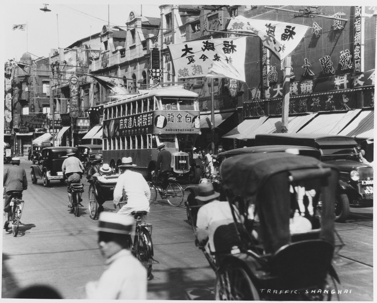 1930s Shanghai street scene showing a public bus with an advertisement for 'Golden Dragon' cigarettes by Nanyang Brothers.