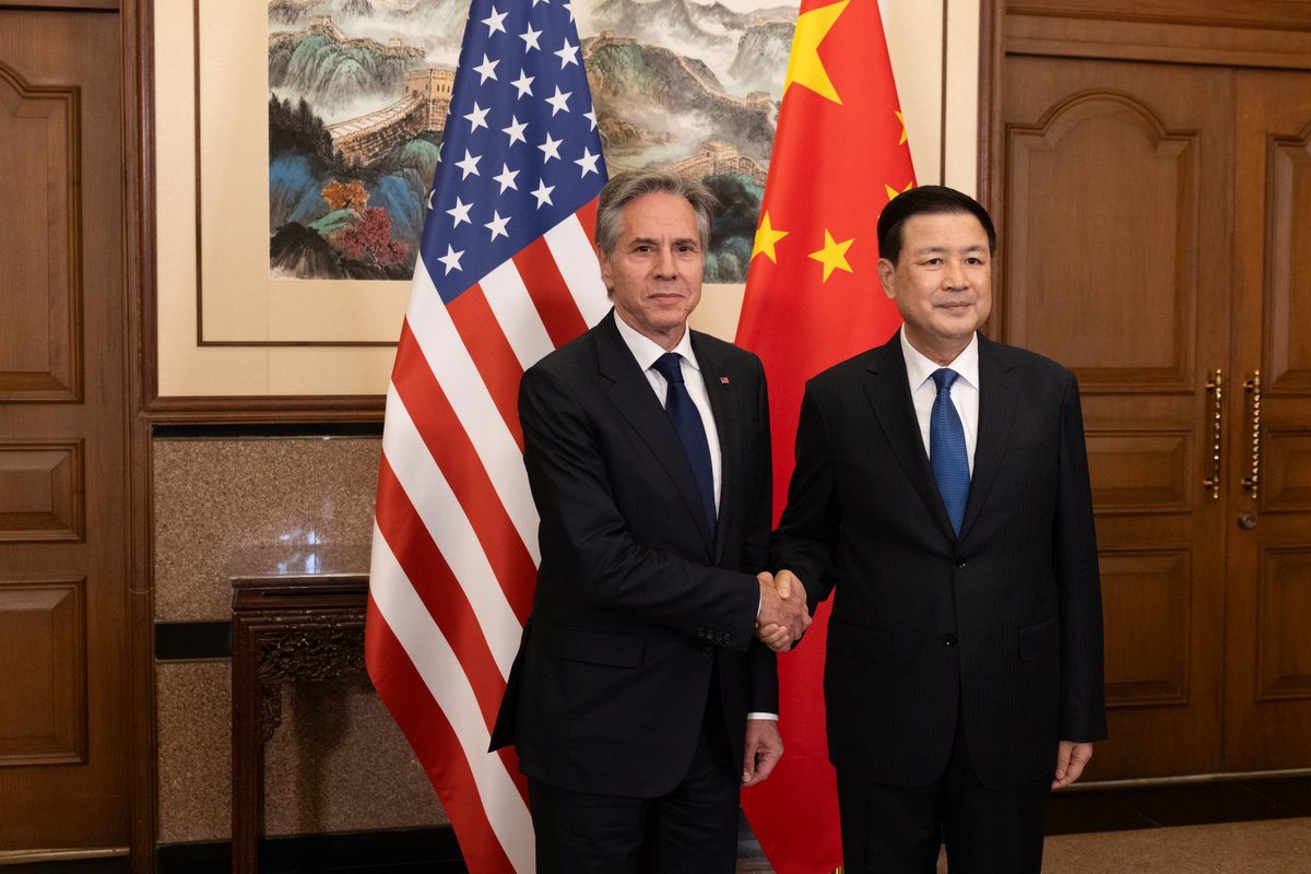 Secretary Blinken stands next to and shakes hands with Minister of Public Security Wang Xiaohong in Beijing, China on April 26, 2024. Behind them, the U.S. and Chinese flags are displayed.