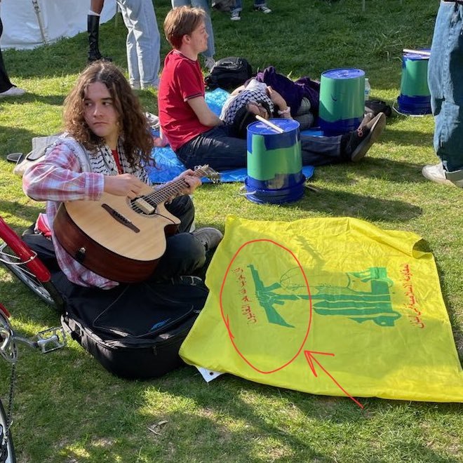 How stupid should they be to call themselves “peace activists”, while sitting next to the flag of Hezbollah terrorist organization 👇 I bet they think the AK-47 rifle on the flag is a guitar 🎸