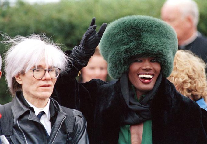 Andy Warhol and Grace Jones, outside St. Francis Xavier Church in Hyannis, Massachusetts on this date April 26 in 1986 after attending the wedding of Maria Shriver and Arnold Schwarzenegger. Photo by Jeff Markowitz. #OTD