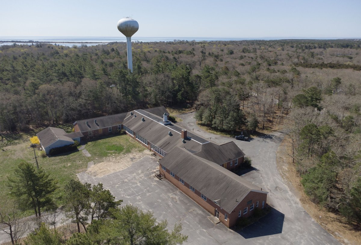 The old Cotuit Elementary School, now vacant, adjacent to a water tower for the Cotuit Fire District. The district has a special meeting on May 4 to discuss the future of the school property. @capecodtimes