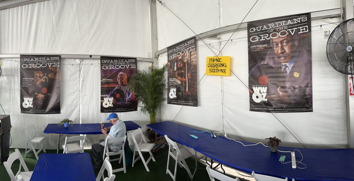 This corner of @wwoz_neworleans hospitality tent for brass pass holders at @Jazzfest at the @FairgroundsNola includes 4 banners from New Orleans Guardians of the Groove! Also great is that they all recorded on this label. Got my fruit & iced coffee. Headed to Jeremy Davenport.