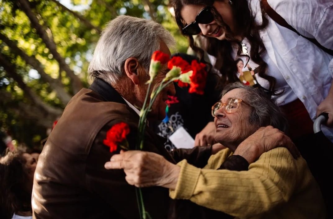 Os comunistas Jerónimo de Sousa e Celeste Caeiro, que distribuiu cravos aos soldados há 50 anos, abraçam-se na Avenida da Liberdade. A fotografia é de Catarina Alves.