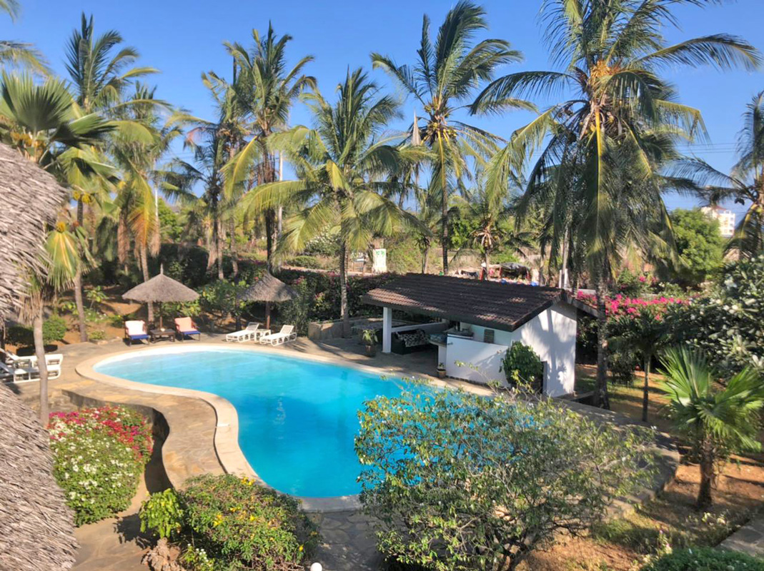 4-Bedroom Villa on Jacaranda Road near beach and amenities. Traditional-style layout with TV room, dining area. Ocean views from second-floor platform, lush garden with pool. Italian-style bungalow with two bedrooms. Separate title deeds. Price: Ksh 75 million.