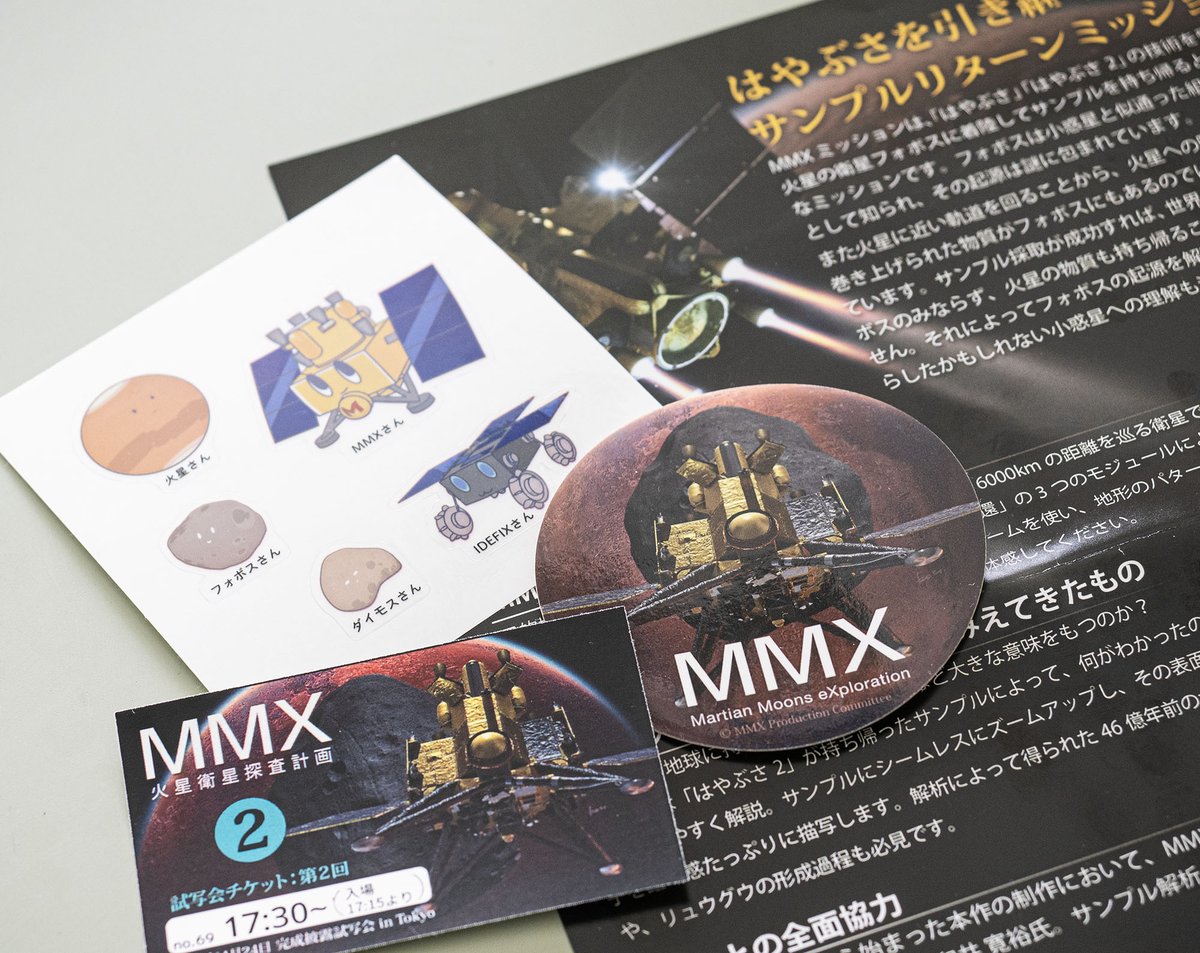 #MMX 試写会その3。マリネリス渓谷正面の火星とMMX。探査計画を辿りながら火星名所巡りも楽しめる。2枚目は川勝プロマネの背中。このMMXジャンパーちょっと欲しい。3枚目はMMXゆるキャラステッカーなどの戦利品。JAXA広報はこの路線でいくらしい……（もっとやれ👏）