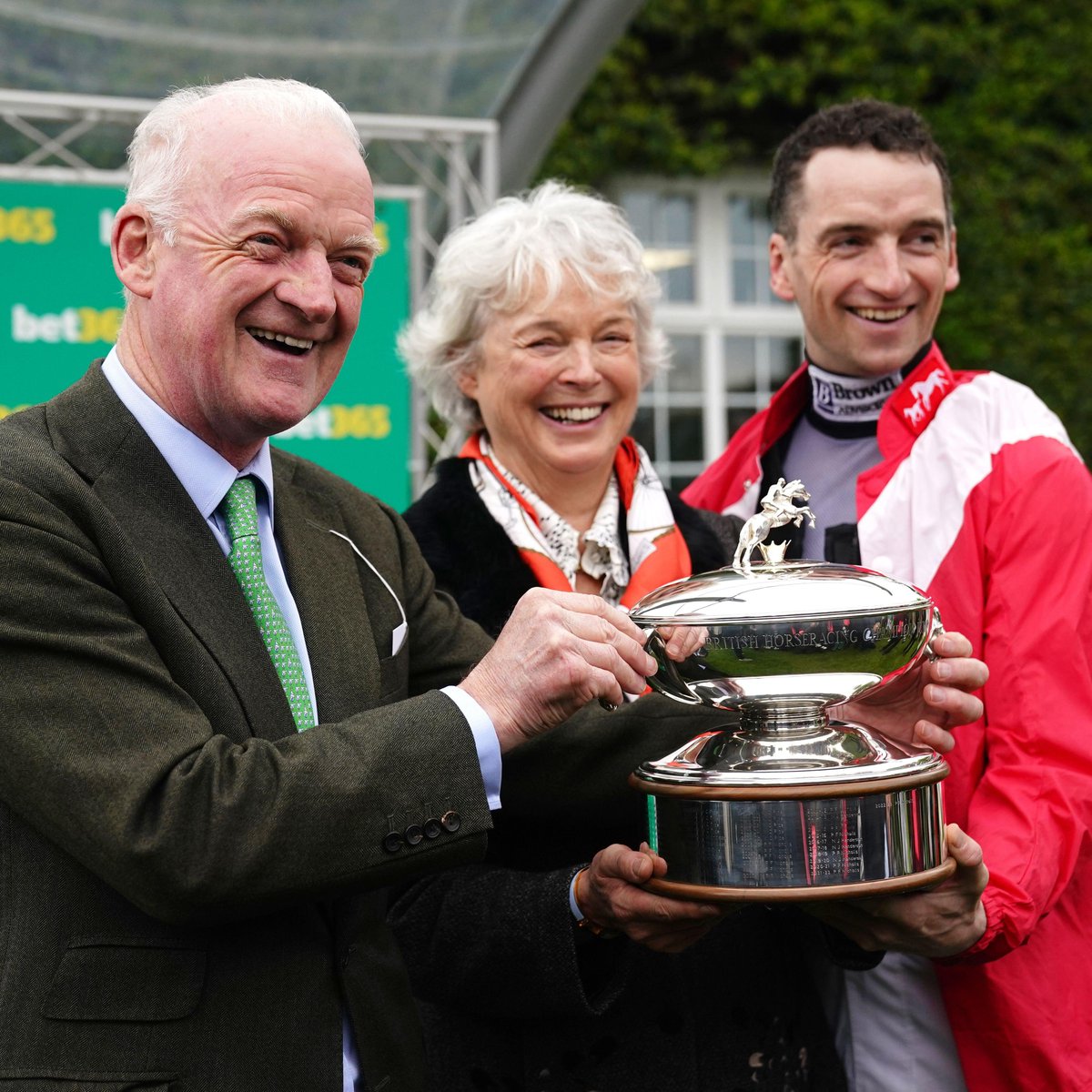 SportingLife's tweet photo. A lovely moment for the Mullins family as Willie, Jackie and Patrick lift the UK Trainers Championship trophy at @Sandownpark 🏆 https://t.co/rqqIL3qYN0