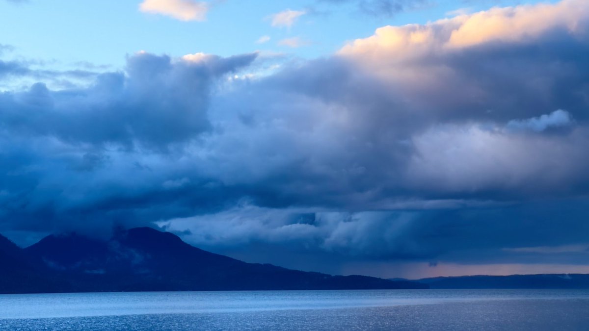 A moody, dramatic sunset over Hood Canal with the clouds catching the tips of the Olympic Mountains.