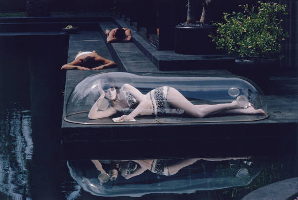 As two men sunbath of the deck of a swimming pool, a model in a two piece bathing suit reads a book as she lies under a clear, bubble cover story (Hollywood, CA, 1964) by Lawrence Schiller
#readingissexy