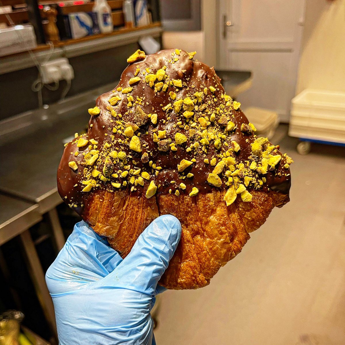 a croissant but flattened, dipped in chocolate ganache & covered in pistachios?