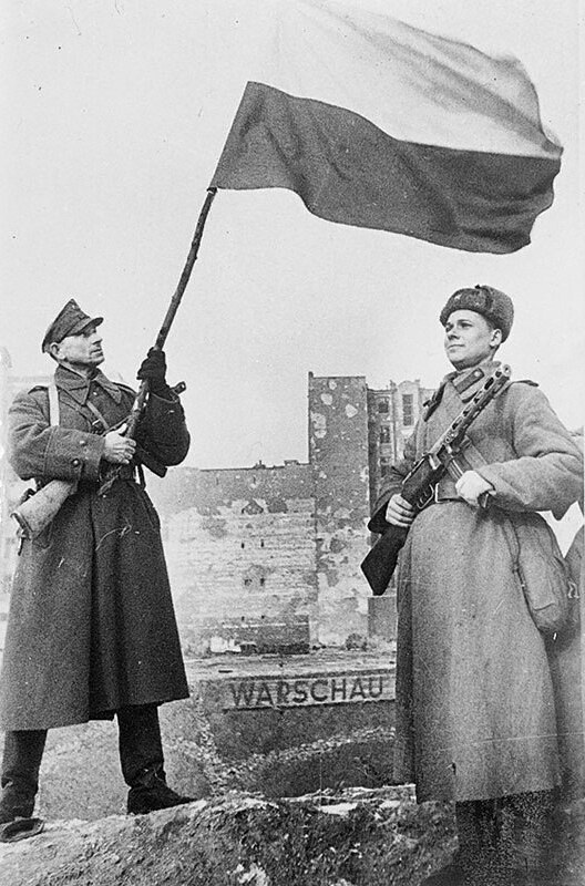 Soviet and Polish soldiers raise the Polish flag over liberated Warsaw, January 1945 (photo by Anatoly Morozov)