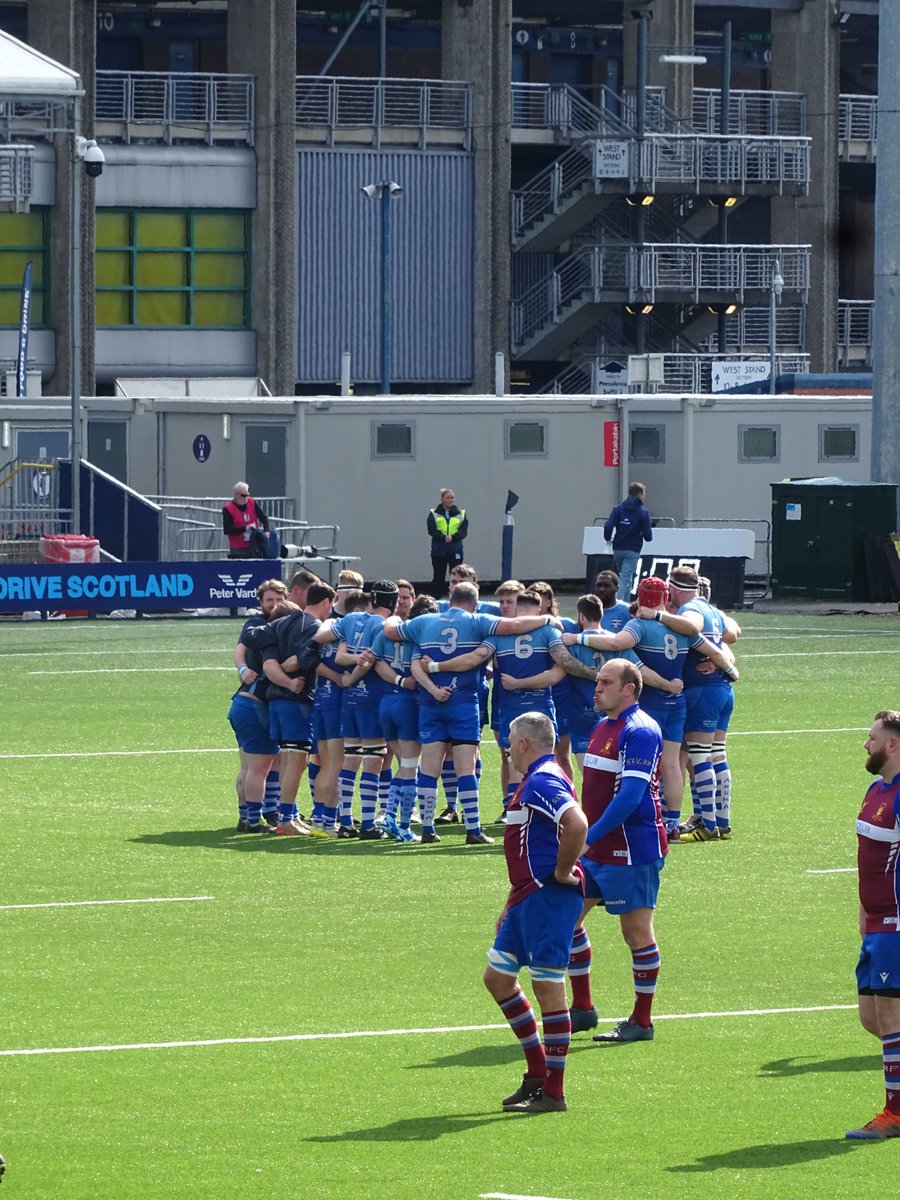 The Blair guys in their pre - match huddle . The game was played at the Hive stadium , part of the Murrayfield complex .