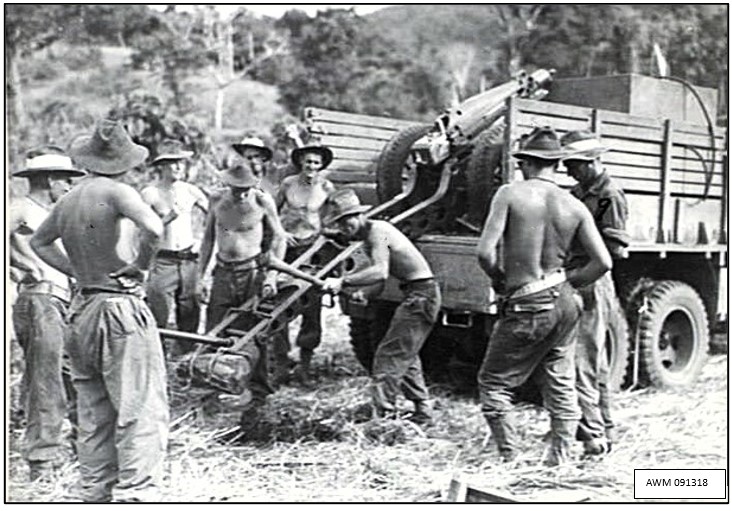 New Guinea, near Wewak. April 1945: In stifling humidity men of Australian 2/1 Tank Attack Regiment watch one dig a pit for the gun trail of a 75mm Pack Howitzer mounted on a truck so it could attain a high elevation for firing on Japanese troops dug in on a high nearby feature.