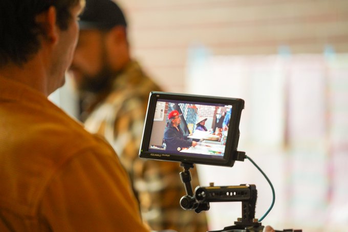 A Children of the Setting Sun Productions team member films an artist at a table during the event