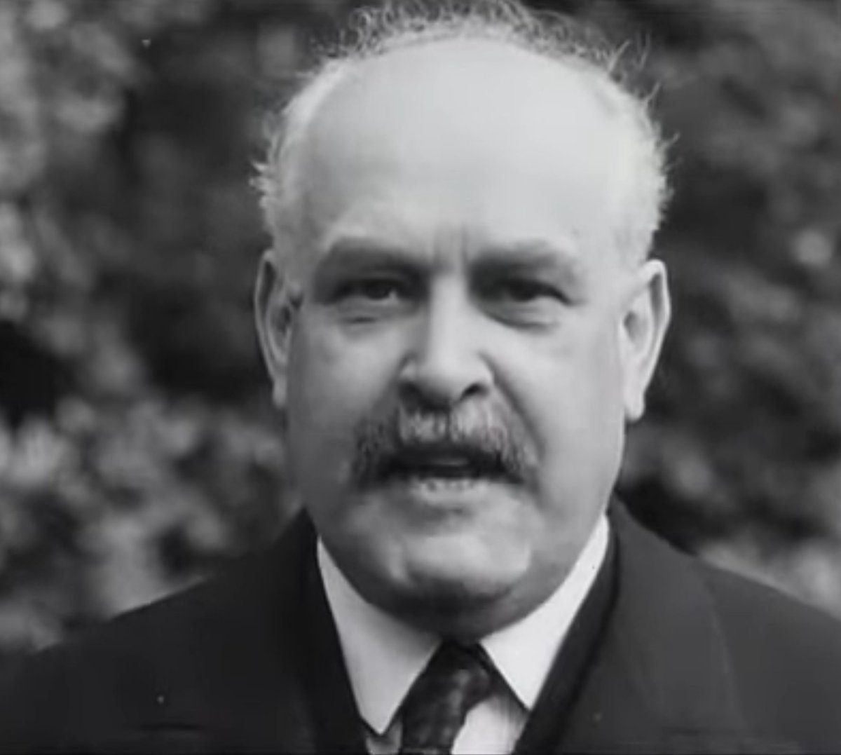 Did you notice the director's tie being askew? His name was Sir Josiah Stamp, an industrialist and banker—second wealthiest man in England. Refusing to move out of his London home during the German air raids of '41, he was tragically killed by a direct hit at age 60.