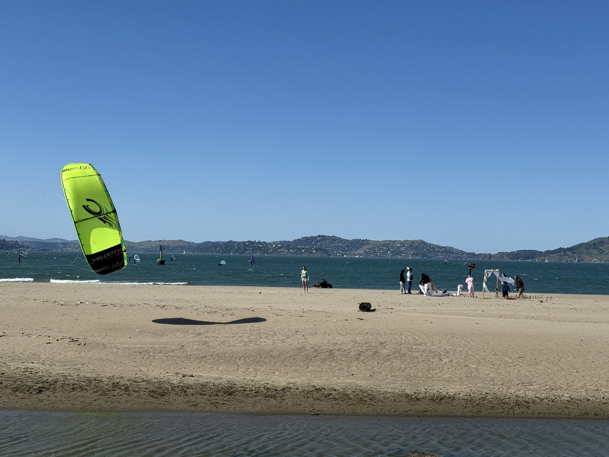 There’s a wedding party trying to shoot some cheesy marriage scene, it’s blowing enough to be a small craft advisory, kiteboarders flying all around them, and they’re trying valiantly to keep it from blowing to oblivion. Impressive.