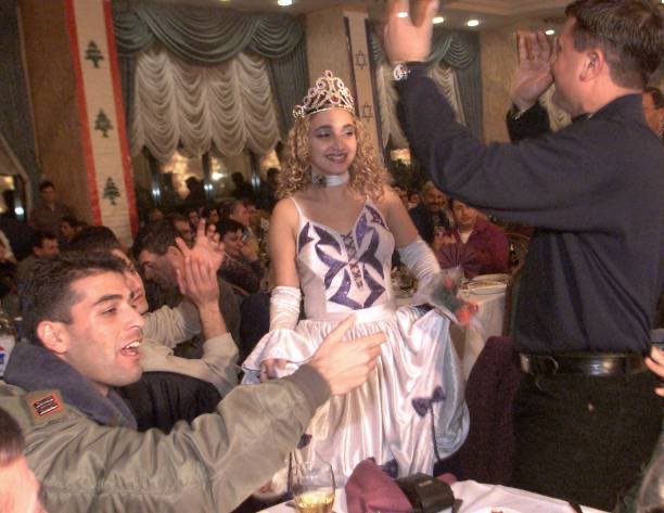 An Israeli soldier (L) and a South Lebanese Army militiaman (R) dance with a Russian-born Israeli dancer during a New Year party held late 13 January 2000