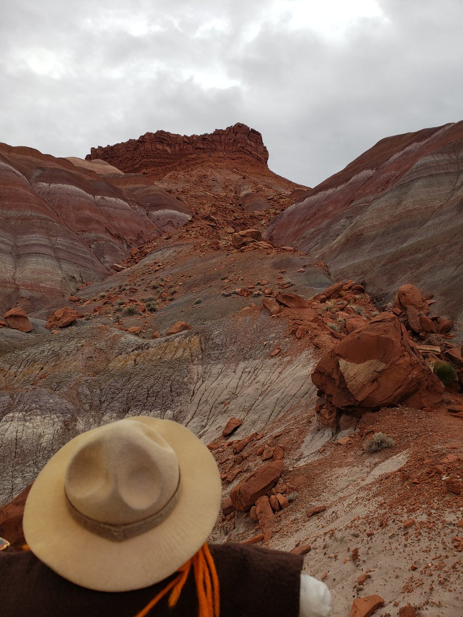 Ranger Sarah look up a small gap in the rainbow colored mountain that has a lot of rock fall from the top of the mountain. — at Grand Staircase-Escalante National Monument. #adventuresofrangersarah #rangersarah #outdoors #nature