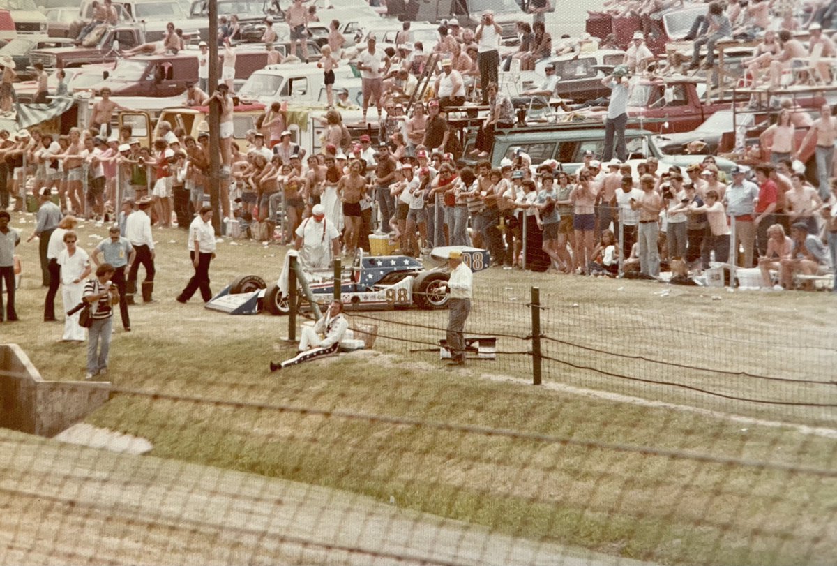 Gary Bettenhausen. 1977 #Indy500 on the backstretch entering Turn 3 - Lap 138 drops out with clutch trouble. Pulls off the track to cool off & a shirtless dude in short shorts vaults the fence & hands him a cold beer.🇺🇸 Car sponsored by J.C. Agajanian & Evil Knievel🇺🇸🇺🇸