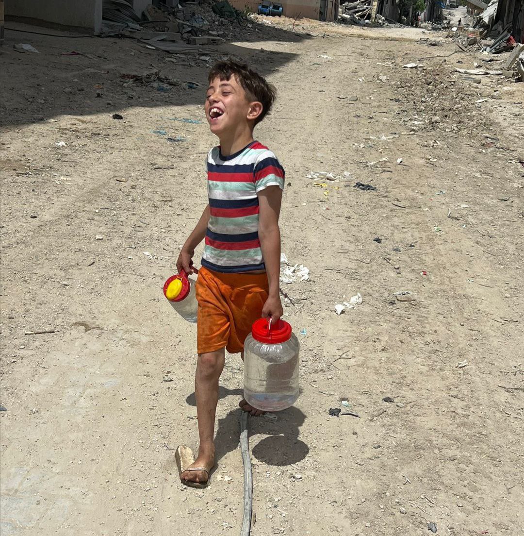 A barefoot, displaced Palestinian CHILD is all smiles after successfully filling in two small jars with potable water.

#ICJ_evidence #IsraelNewNazisim #WorldGlobalStrikeForGaza