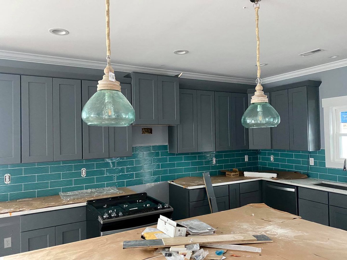 We added cabinets to the back of the island, green glass wavy backsplash, a custom ceiling fan with sails, fireplace, and a large master shower.