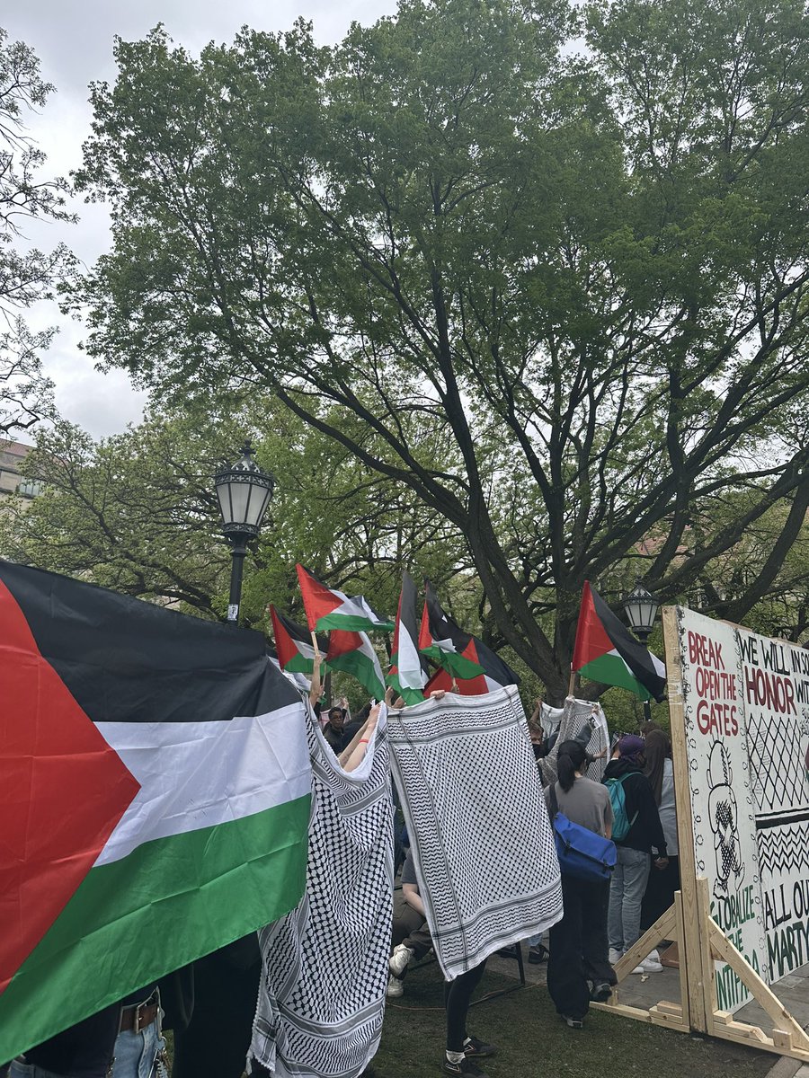 AT UCHICAGO: students forming a wall with flags, kuffiyehs, the apartheid wall, and their bodies to prevent agitators from disrupting duhur prayer