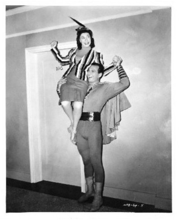 Tom Tyler giving comedienne Judy Canova a boost backstage at Republic Pictures. Judy appreciates the view from above as well as Tom's Captain Marvel #Shazam muscle power. #RepublicPictures #TomTyler #comicbook #CaptainMarvel #JudyCanova #champion #superheromovie #weightlifting