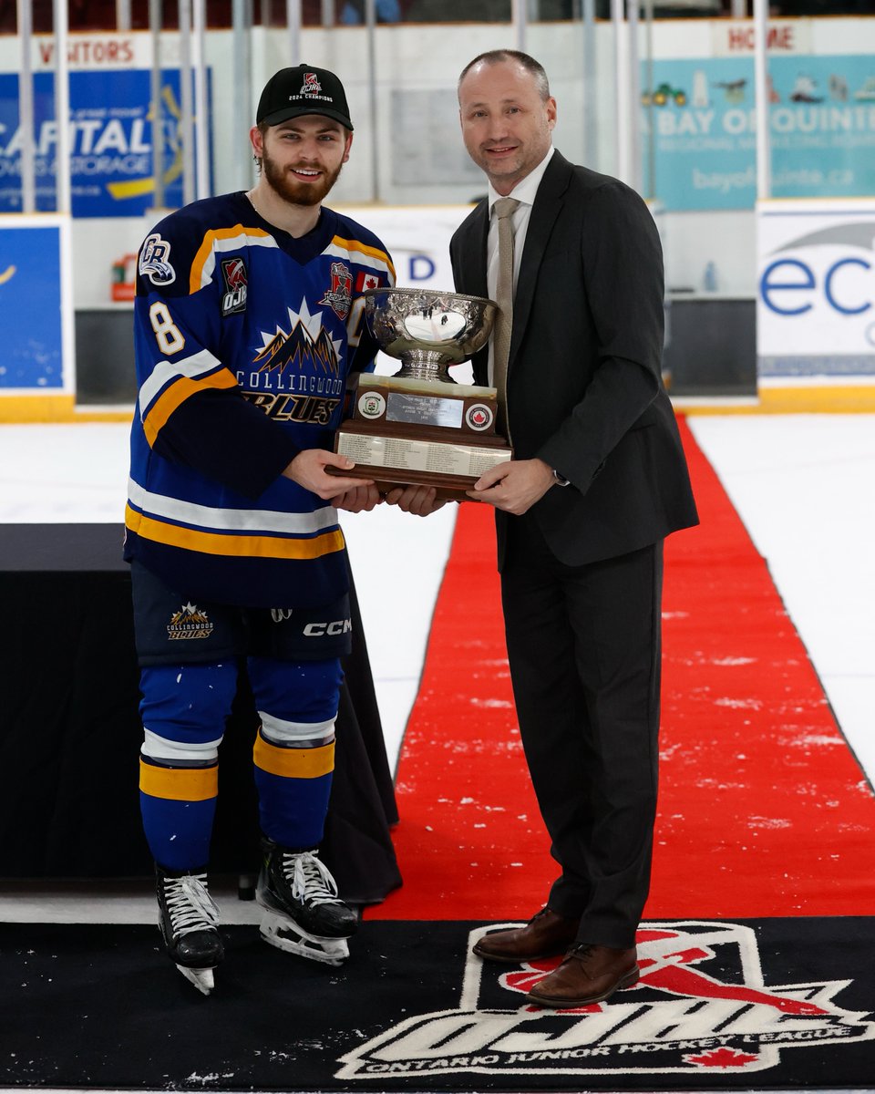 TRENTON, ON - APRIL 29: OJHL Commissioner Marty Savoy presents the Buckland Cup to team Captain Dylan Hudon #8 of the Collingwood Blues at the Duncan McDonald Memorial Community Gardens on April 29, 2024 in Ontario, Canada (Photo by Tim Bates / OJHL Images)