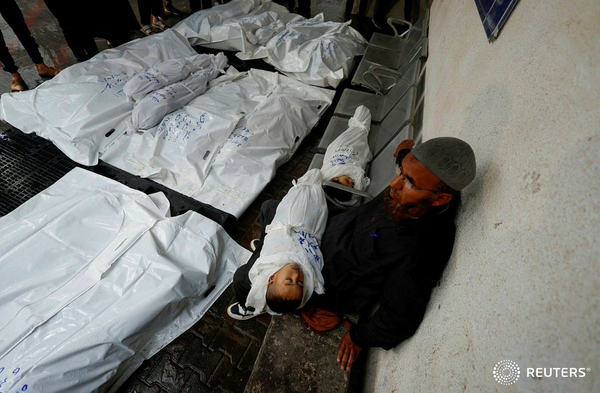 A mourner holds the body of a child as he sits next to body of another child and of other Palestinians killed in Israeli strikes, during their funeral, at Abu Yousef al-Najjar hospital in Rafah, in the southern Gaza Strip, May 6, 2024. REUTERS/Mohammed Salem