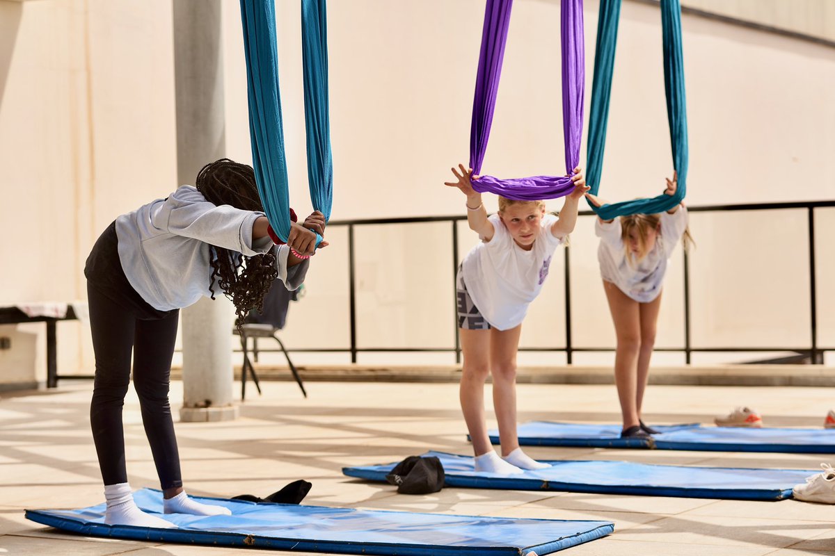 ISDakar's tweet photo. With panoramic views of the glistening Atlantic ocean and a warm breeze, aerial yoga is one of our most engaging enrichment class activities. Our students learn flexibility, yoga, pilates and dance skills all in one. #ISDakar #Yoga #AerialYoga https://t.co/dTTs1N1NNY