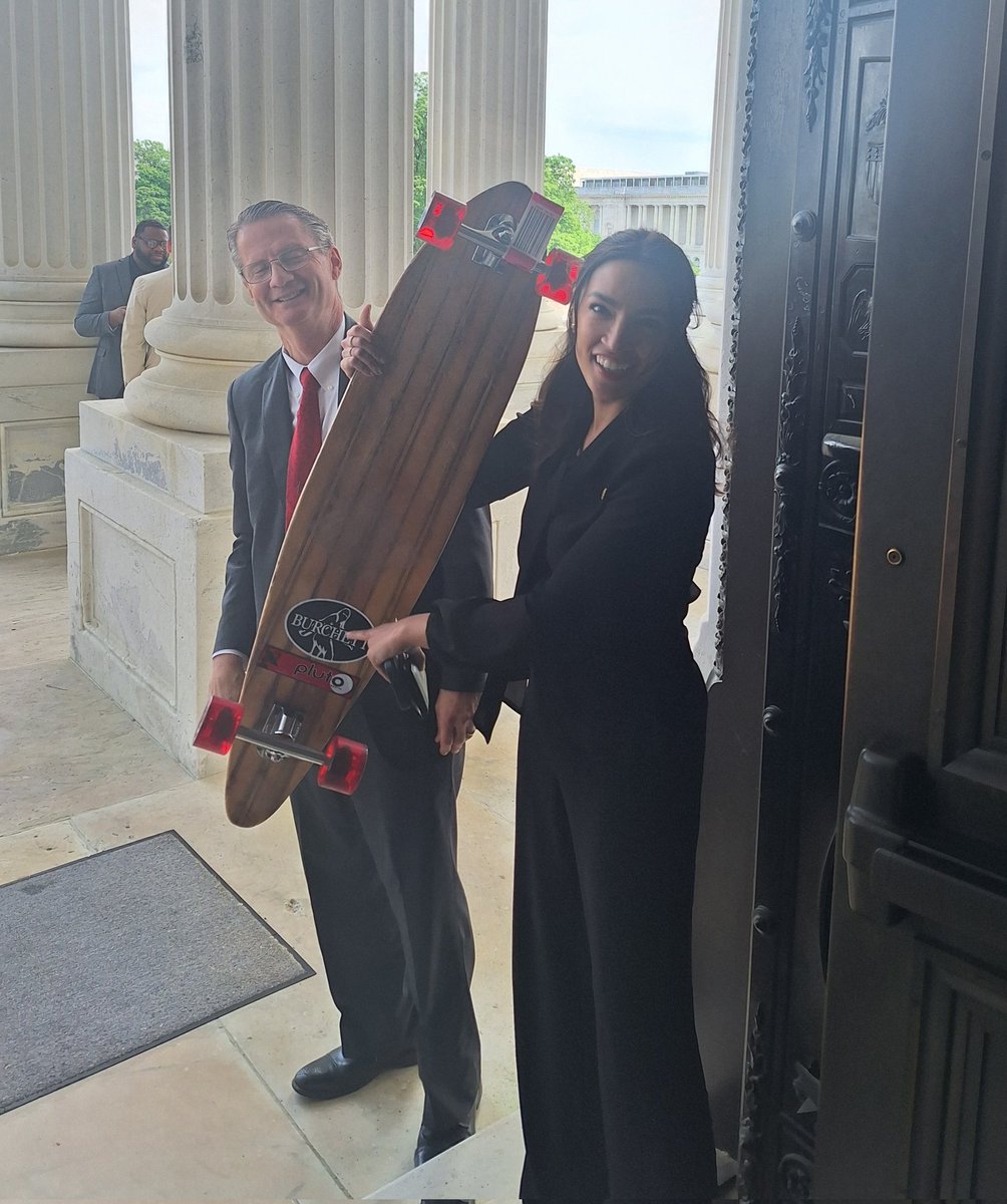 @timburchett brought a longboard to the House today, which he said he crafted himself from scrap wood he found on the side of the road. 'I'm upcycling!' he told @AOC, who seemed to like it