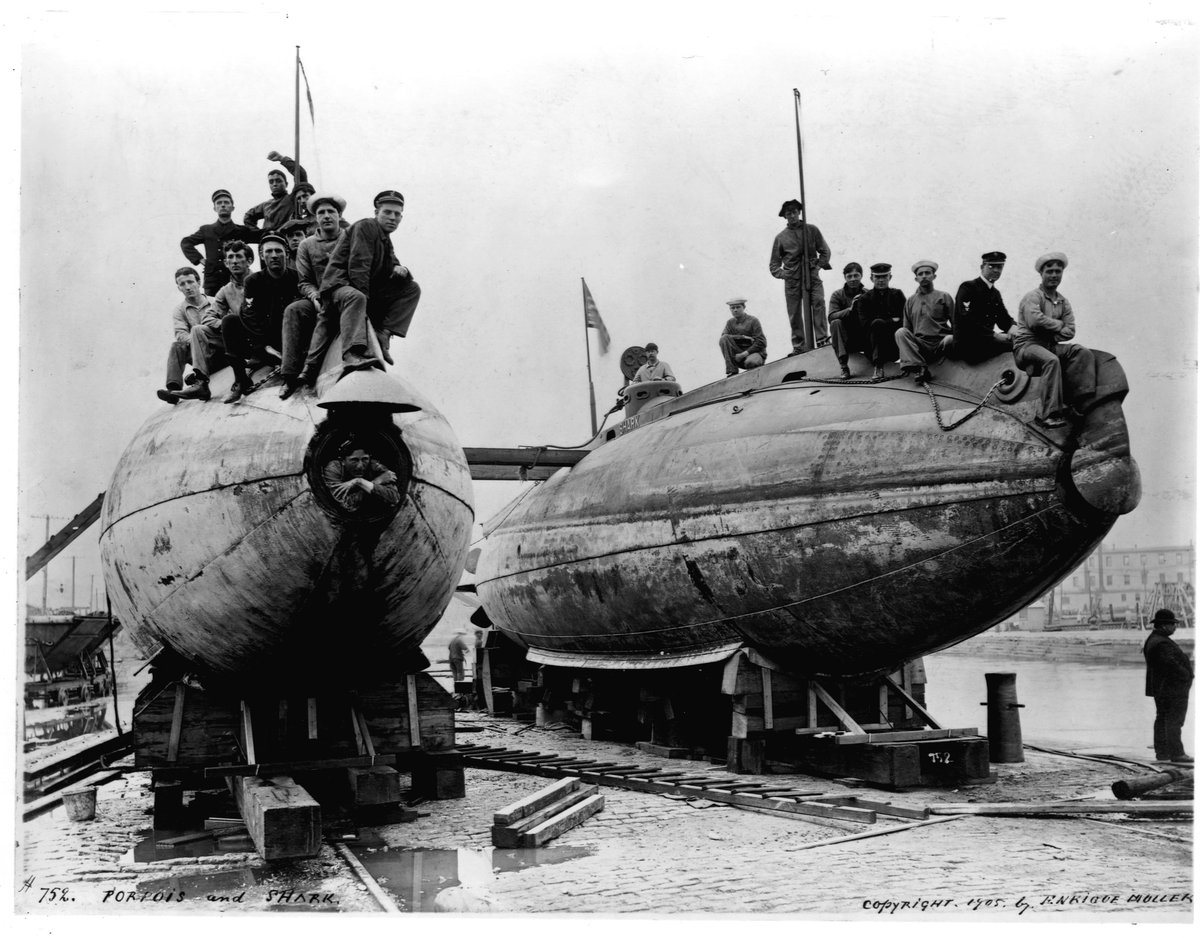 US Navy sailors sit on the bows of the drydocked submarines USS Porpoise (SS-7) and USS Shark (SS-8) on the left, 1905.