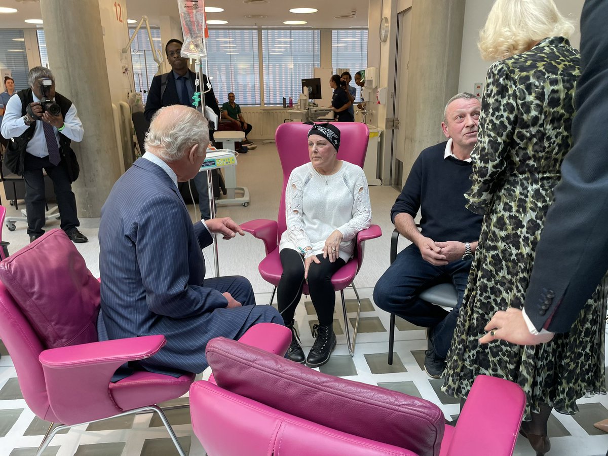 Two cancer patients chatting. 
The King meets Leslie Woodbridge while she is having her chemotherapy. He’s with the Queen. She’s with husband Roger. She asks “how you feeling?” couldn’t hear the answer.