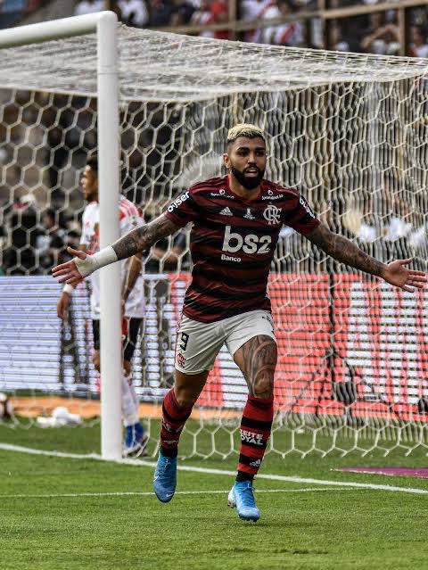 martinFLA81's tweet photo. Dia !

Posso falar ou estaria te incomodando…? Talvez eu me estenda, daquele jeitinho…

O rubro-negro acordou com uma grande notícia hoje. Daquelas que toca na alma, emociona e arrepia.

Ganhar, empatar, perder… Mas ao lado dos nossos. O Flamengo é menos Flamengo quando está distante daquilo que o define.

Como ainda tem o julgamento do mérito daqui um tempo, não diria que nós viramos, de novo, mas bem, esse foi o nosso gol de empate em Lima. O suficiente pro retorno do ídolo à sua rotina normal. Por agora, basta. E como basta…

Costumo dizer que Gabriel não é um herói. Herói? “Mocinho”? Puts, isso zero combina com ele.

Gabriel é um anti-herói rubro-negro.

“O anti-herói é considerado a personagem que vai perturbar e, ao mesmo tempo, criar empatia com o espectador, ao conciliar caraterísticas boas e más, defeitos e qualidades, que podem ou não ser equivalentes aos do espectador normal. Ou seja, o anti-herói vive no equilíbrio entre virtudes e defeitos da conduta moral.”

Entre o certo e o errado, entre seus defeitos e qualidades, Gabriel é o que é. E nós, espectadores dessa loucura que é a vida dele, passamos por cima dos julgamentos e da moralidade alheia para defendê-lo. Idolatria é isso, e é divertido pra caralho.

Gostar de Gabriel Barbosa é como ter um irmão. Mais velho ou mais novo, pouco importa. Você vai brigar, discordar, ficar puto as vezes, implicar um com o outro, mas, no final, que bom que ele está lá.

“Em tom de brincadeira, Gabigol disse: “DR com a torcida. Não tem problema, não. É igual nossa mulher. A gente briga, briga, briga, mas a gente ama”.

Ele precisa estar lá. Com ele fica tudo mais divertido. Tenho a sensação que os erros dele são meus também, e seus gols também.

Quando ele, lá embaixo no gramado, balança a rede a gente faz como, seja na arquibancada, no bar ou no sofá?

“Gol do Gabigol!  ᕦ( ͡° ͜ʖ ͡°)ᕤ”

Gol dele é diferente.

Ninguém idolatra e vive seus ídolos como faz a torcida do Flamengo.

Estou emocionado. Vamos beber pra celebrar.

Hoje é sexta 1.

Amanhã, domingo.

Quinta, quinta.

Sexta é sexta 2.

Ops, me desculpe a pausa poética! rs

Eu não sei se você vai ler, @gabigol, mas eu sei que você está sempre de olho, então me permita fingir que sim, tal qual a inocência de uma criança mandando cartinha pro Papai Noel. Ora, ao menos pedi pra Ele a sua absolvição…

É o seguinte…

A torcida do Flamengo está e sempre estará contigo. Seu lugar é no Flamengo. Não deixe, jamais, que engravatados num ar-condicionado ditem o que será do seu futuro no clube.

As ruas estão com você.

Não há lugar, no Brasil ou no mundo, em que você será tão abraçado, , defendido, querido e amado como é no Flamengo. Não há milhão $ aqui, outro ali, que pague isso.

No banco, como titular, machucado, suspenso, pouco importa… Queremos a sua presença, do jeito que for. Até mesmo se for pra te xingar na esportiva, por ter errado algum lance que faz parte do jogo.

Gabriel, nós te queremos. Fique, se aposente aqui, eternize seu tamanho no clube atuando apenas aqui daqui pra frente, ao menos nacionalmente. Os maiores fizeram assim.

O campo fala, ele sempre fala. E talvez a fase recente não muito favorável tenha te feito, num breve momento de estresse, incômodo, pois você é humano e também erra, escorregar no trato com os agentes anti-dopagem e dar brecha pra tudo isso. A resposta deles veio na perseguição besta que você sofreu.

O que é deles tá guardado, ídolo. Ninguém mexe com a torcida do Flamengo e passa ileso. A vida cobra.

Agora? Respirar de alívio e ir pra cima, você sabe o enredo. Calma, paciência, tranquilidade, foco e BUSCAR O SIMPLES. É hora de facilitar.

“Take It Easy”…

Take It Easy My Brother, Gabi.

Vamos lá, nós estamos com você. NÓS ESTAMOS COM VOCÊ. 

Obrigado por existir, do seu jeito, @gabigol. Nosso Guerreiro Galáctico.

Você não desistiu de nós em Lima.

Você não desistiu de nós em 2020.

Não vamos desistir de você.

Nunca.

Nas boas e nas ruins, juntos.

Nós vamos virar essa porra, de novo.