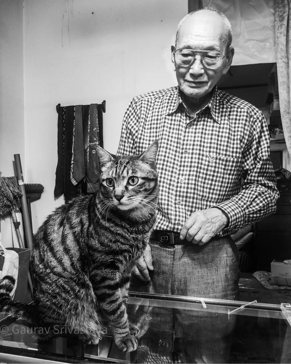 A seasoned watchmaker at work in his fifty-year-old shop, while his ten-year-old cat Mi-chan keeps the customers entertained. #blackandwhite #portraitphotography #Tokyo #Japan #CatsOnTwitter