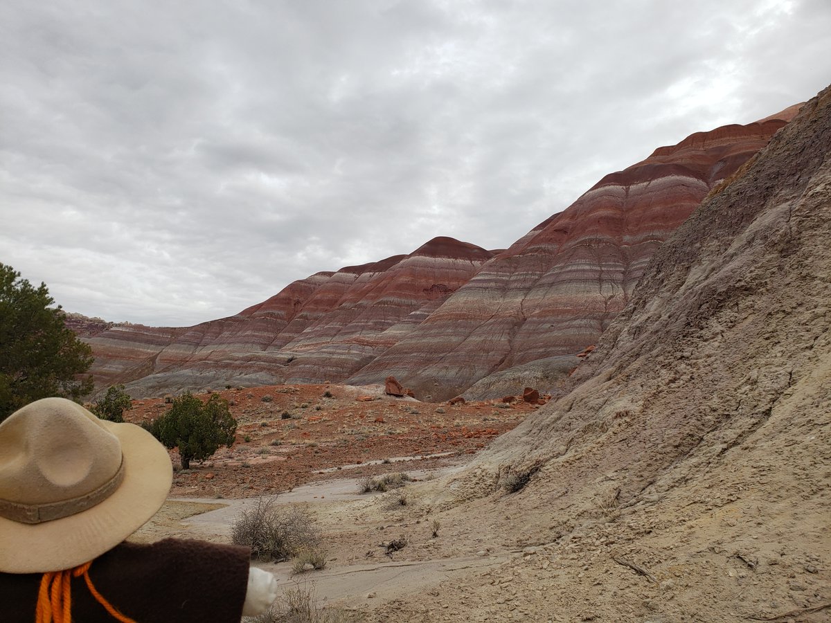 Ranger Sarah with another amazing view of the Rainbow Mountains. The vivid hues are attributed to the encrustation of iron oxides, manganese, cobalt, & others. These minerals have leached into the rock layers over time, staining them with shades of red, purple, yellow, & blue.
