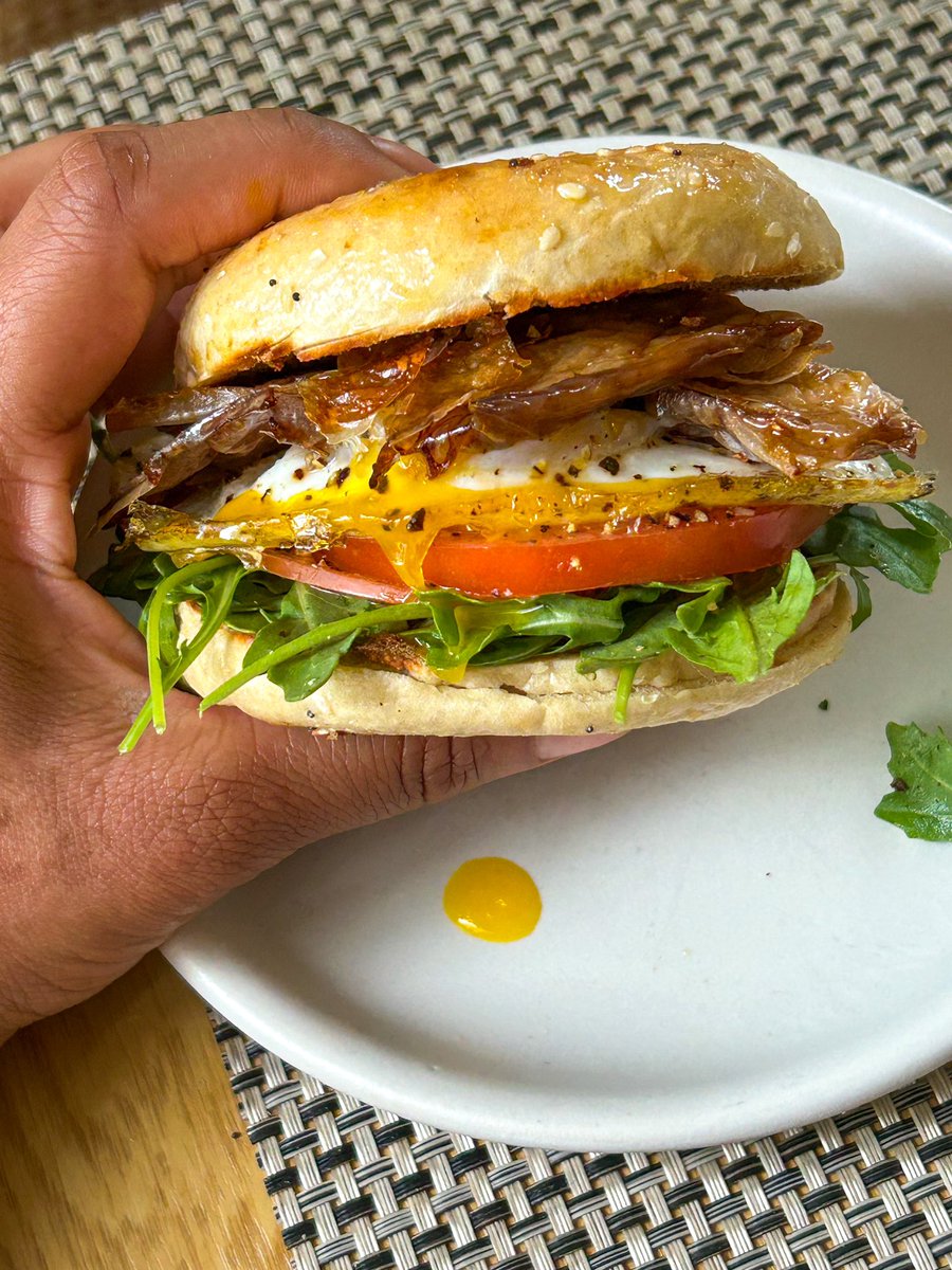 Bagel sandwich with arugula, tomato, oyster mushroom bacon and a fried egg.