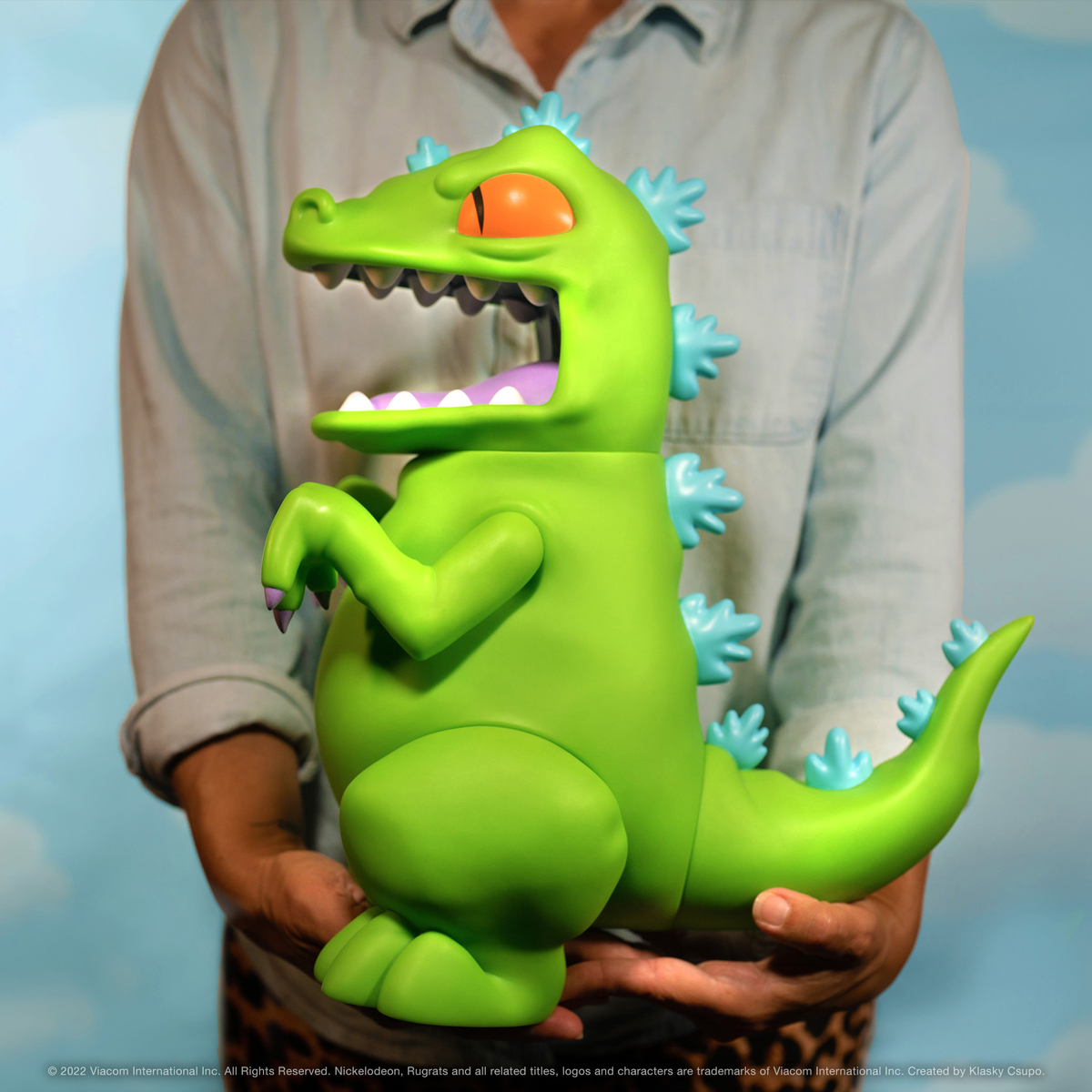 This Supersize Reptar figure measures 16” tall and 13” long from snoot to tail, and features a poseable head, arms, legs, and tail. With bright green skin, big teeth, purple tongue, orange eyes, and blue spikes all along its back and tail. Shop now on Super7.com!