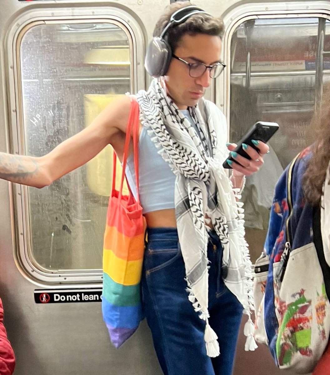 Man wearing a crop top wears a Palestinian keffiyeh scarf alongside an LGBTQI+ bag. Do these two things go together? 🏳️‍🌈🇵🇸 📸 @MichaelRapaport