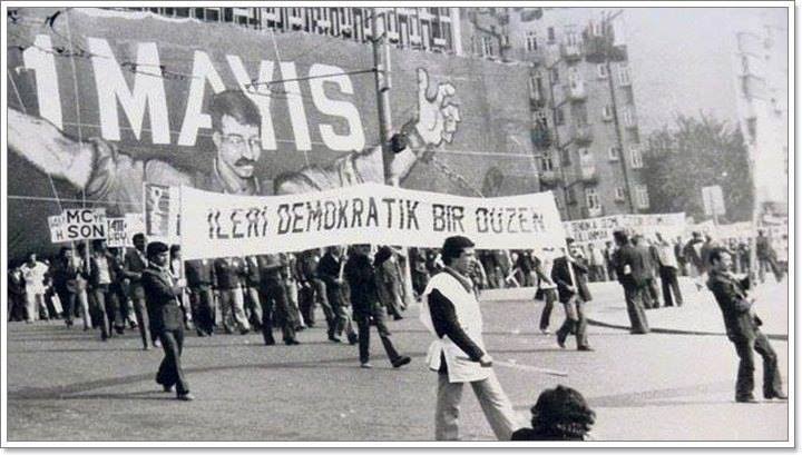 Bir elimde ekmeğim
Bir elimde onurum
Düşürmeden yere
Bir bayrak gibi 
Alnımda kızıl ateş
Yürüyorum meydana
Namlu puşt olmuş 
Yasal kurşun kalleş
Kan fışkırır sırtımdan
Gözlerimden ateş
Düşerken tertemiz alnım  yere
Dilimde aynı slogan
'Kahrolsun kapitalizm 
YAŞASIN #1MAYIS '