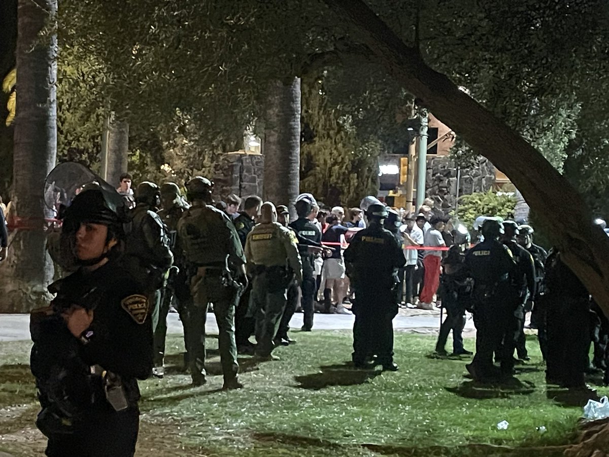 SWAT OFFICERS HAVE ARRIVED TO THE UA ENCAMPMENT WITH GUNS CARRYING PEPPER BALLS. THEY ARE MOVING TOWARDS THE BARRICADED STUDENTS.