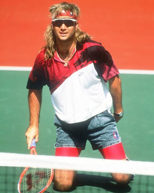 Andre Agassi rocking acid washed Nike denim shorts at the 1988 US open. Agassi was an absolute rebel in the 90s when it came to the tennis dress code and rocked fluorescent shirts and sported a rock n roll shag hairdo.
