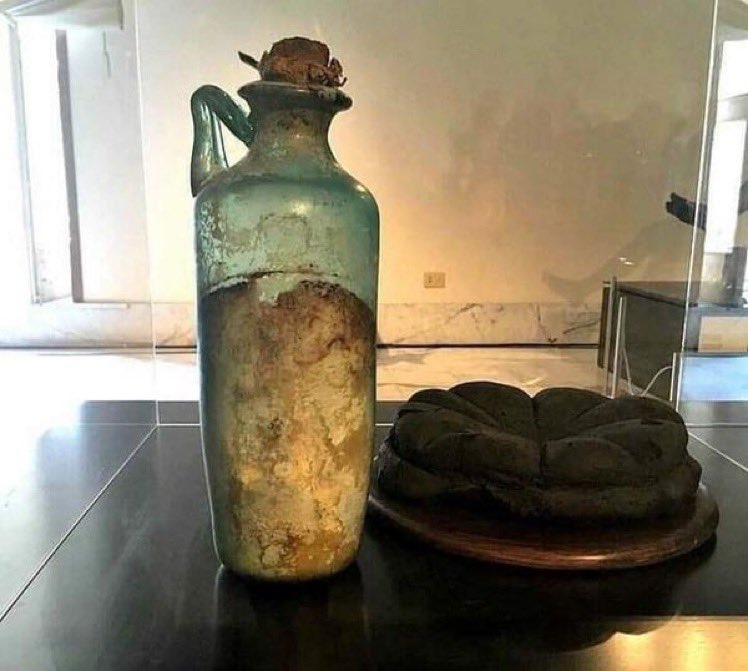 Left: Wall painting from home in #Pompeii showing olive oil and round loaf of Roman bread. Right: Bottle of olive oil and carbonized bread that survived the 79 CE eruption of Vesuvius. (Bottle still contains oil!) From a display at #Naples' Archaeological Museum.